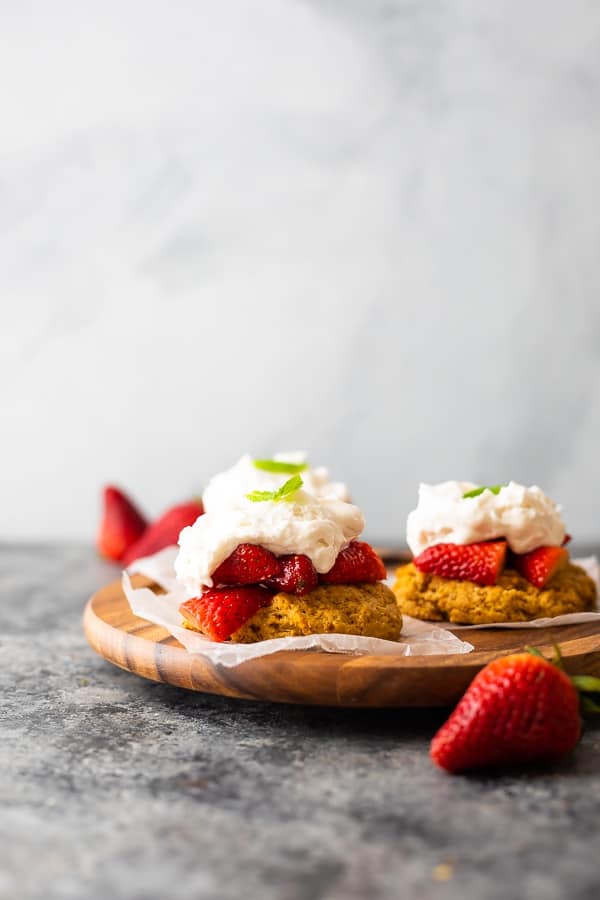 how to make strawberry shortcake: showing assembled strawberry shortcakes on wooden plate