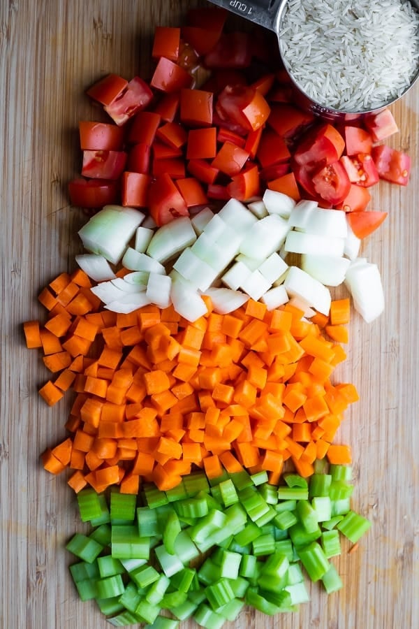 chopped tomatoes, onion, carrot, and celery on a cutting board