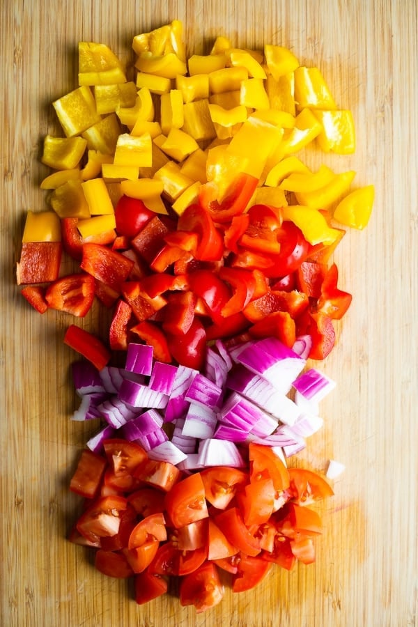 overhead shot of ingredients for Instant Pot Fiesta Rice Bowls including yellow pepper, red pepper, red onion, and diced tomatoes