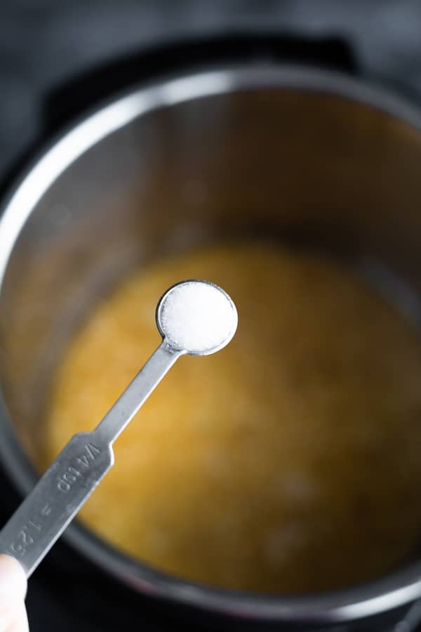 teaspoon of salt being added to quinoa in the instant pot 