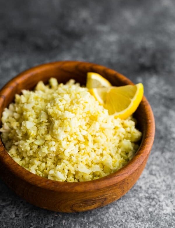 Lemon garlic cauliflower rice in a wood bowl with lemon slice garnish