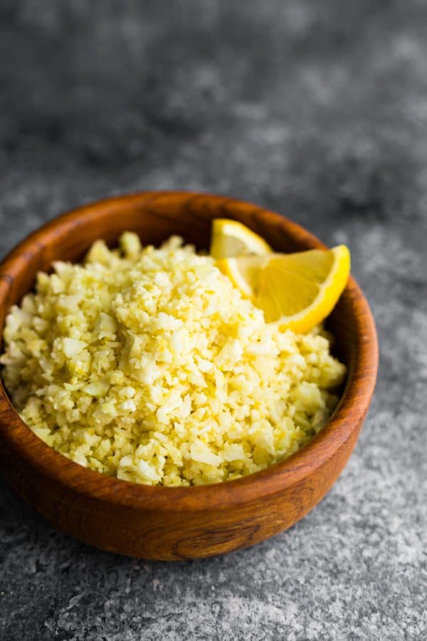 Lemon garlic cauliflower rice in a wood bowl with lemon slice garnish