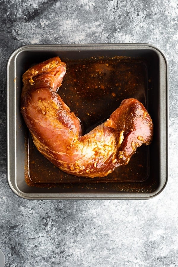 pork tenderloin marinating in grilled pork tenderloin marinade in a baking dish