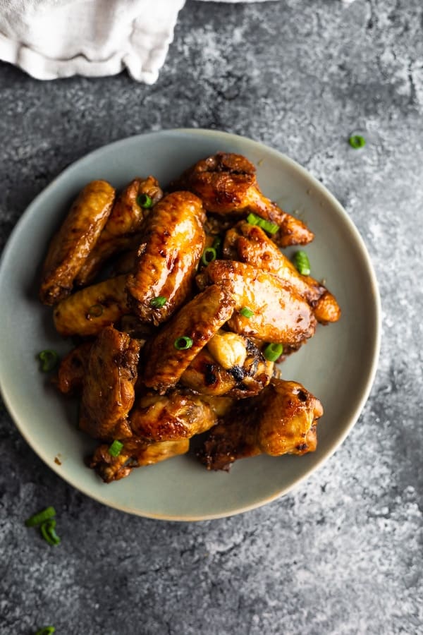 cooked crockpot chicken wings on plate with green onions