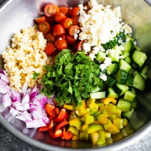 Large mixing bowl with all the ingredients for summer couscous salad