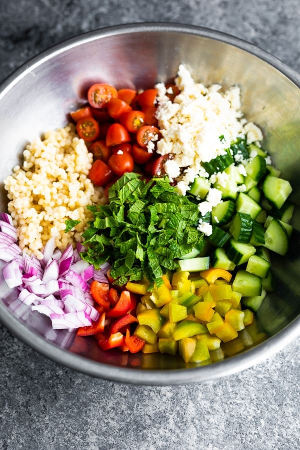 Large mixing bowl with all the ingredients for summer couscous salad