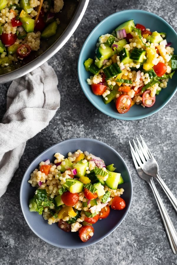 israeli couscous salad recipe in two bowls with forks