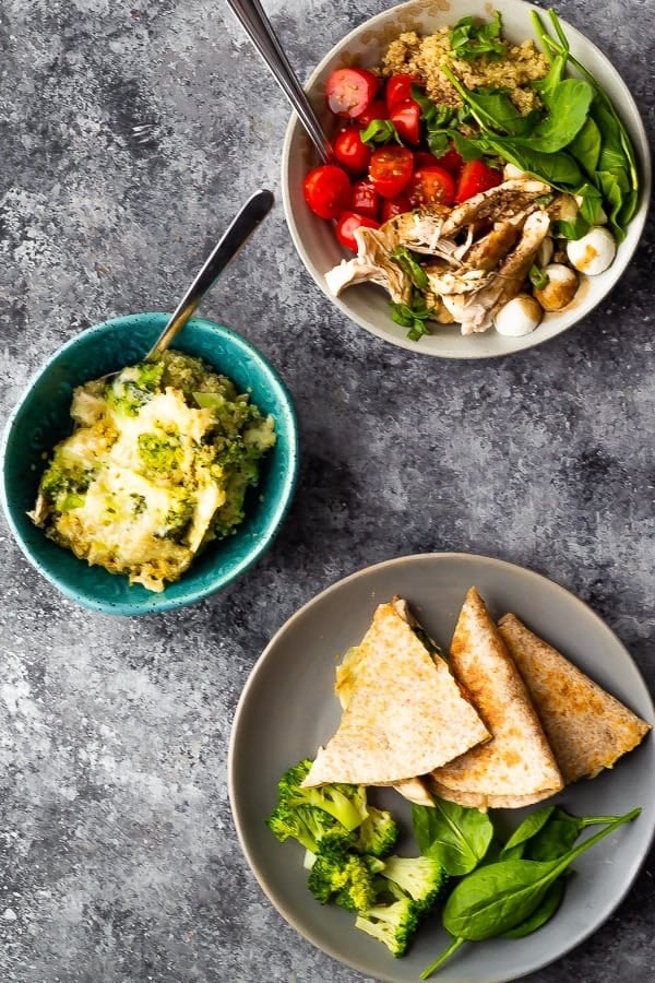 overhead shot of blue and gray bowls and plates filled with variety of dishes made from whole chicken meal prep