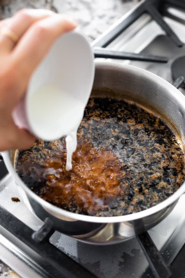 adding corn starch and water to teriyaki sauce in a pot on the stove