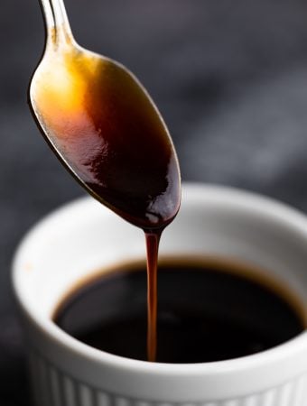 Close up of a spoon dripping homemade teriyaki sauce into a bowl