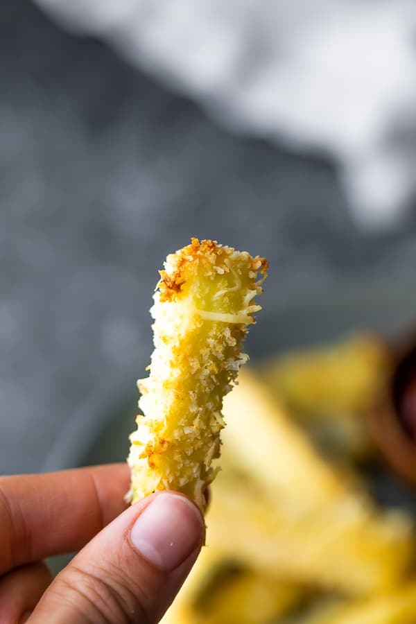 close up of zucchini fries held by hand