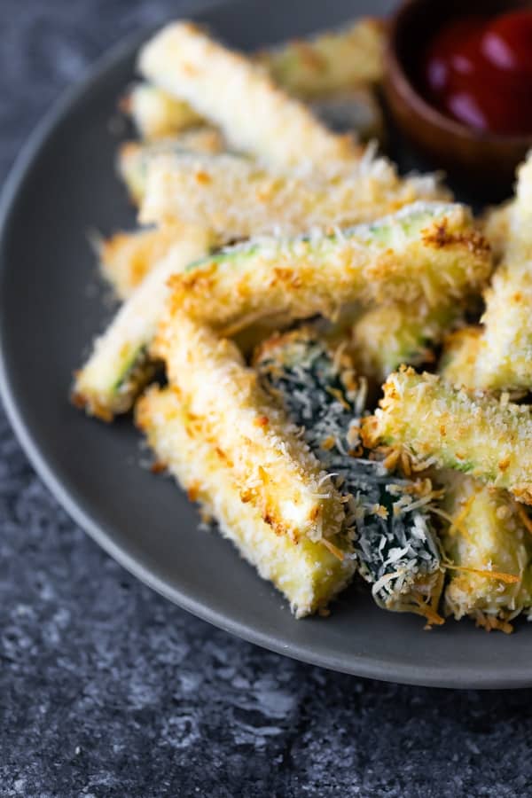 close up of baked zucchini fries on grey plate
