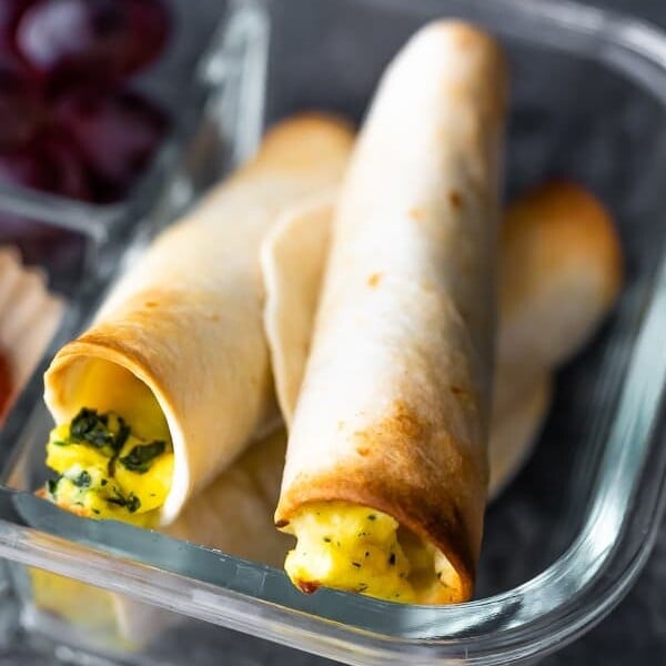 Three breakfast taquitos in a glass meal prep container