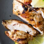 close up shot of sliced chicken with greek marinade and lime slices
