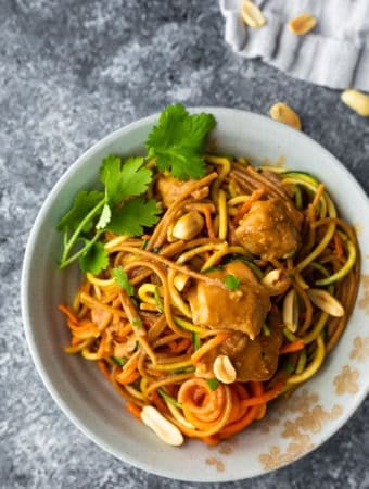 overhead shot of spicy instant pot peanut noodles in white bowl with cilantro and peanuts