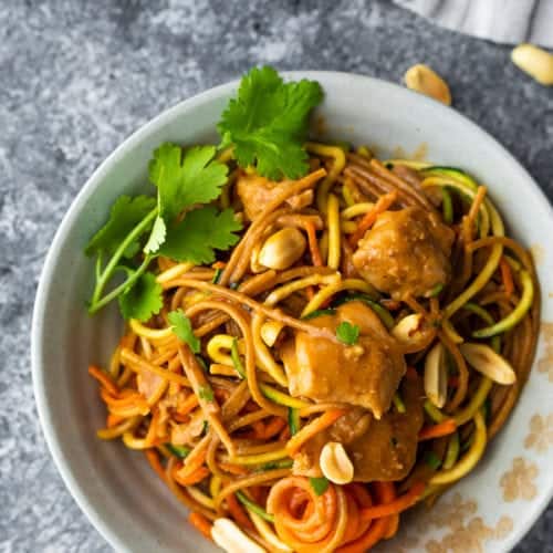 overhead shot of spicy instant pot peanut noodles in white bowl with cilantro and peanuts