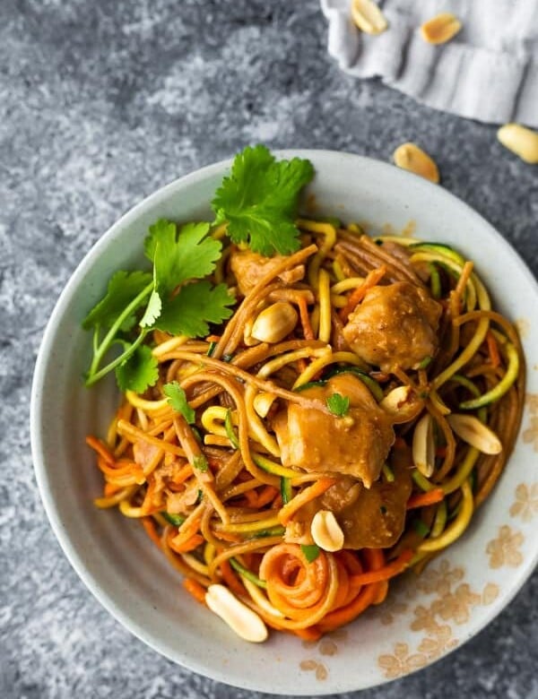 overhead shot of spicy instant pot peanut noodles in white bowl with cilantro and peanuts