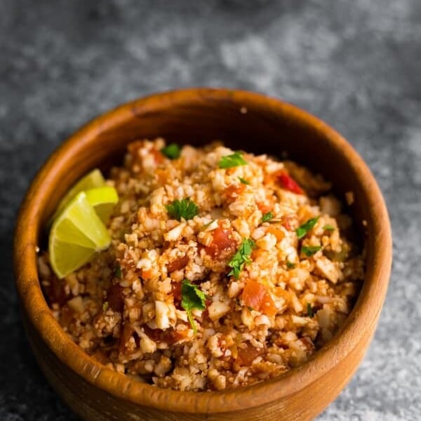 wood bowl filled with mexican cauliflower rice and lime wedges
