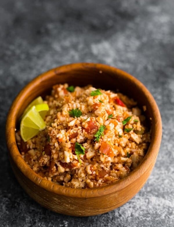 wood bowl filled with mexican cauliflower rice and lime wedges
