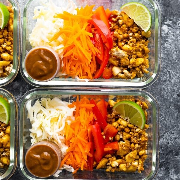 overhead shot of tofu spring roll bowls in glass containers with lime wedge and dressing