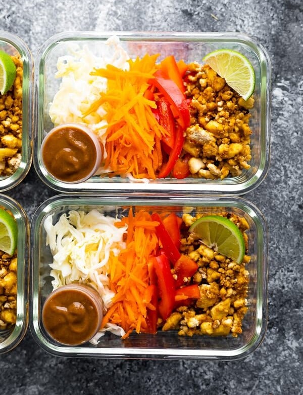 overhead shot of tofu spring roll bowls in glass containers with lime wedge and dressing