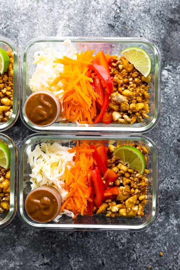 overhead shot of tofu spring roll bowls in glass containers with lime wedge and dressing