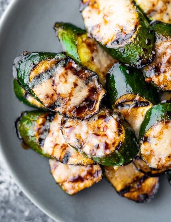 balsamic grilled zucchini with parmesan in a pile on gray plate