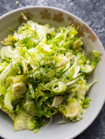 overhead shot of apple, fennel, brussels sprouts slaw in gray bowl