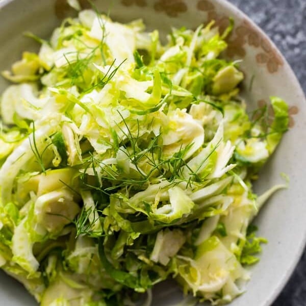 overhead shot of apple, fennel, brussels sprouts slaw in gray bowl