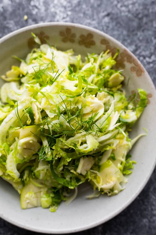 overhead shot of apple, fennel, brussels sprouts slaw in gray bowl