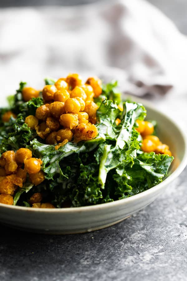 side view of kale caesar salad with garlic chickpeas in gray bowl