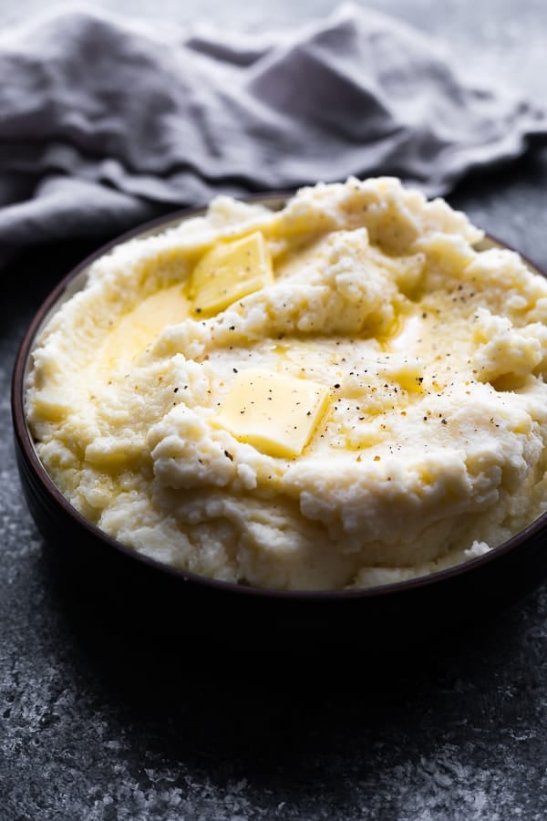 close up shot of mashed cauliflower in bowl with melted butter