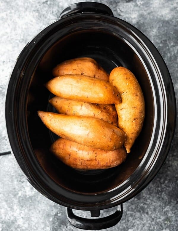 overhead shot of whole sweet potatoes in crock pot