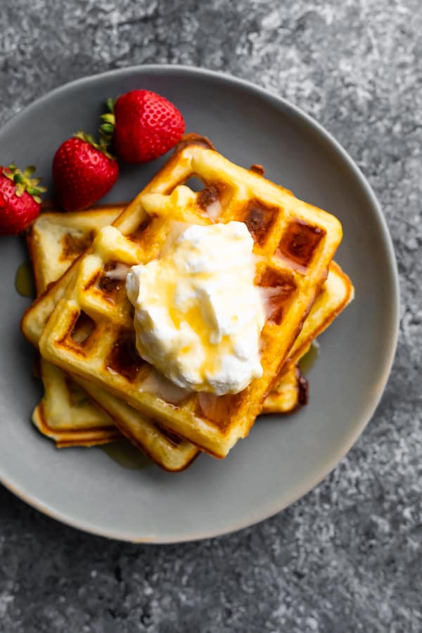 overhead shot of crispy buttermilk waffles with syrup and fresh strawberries