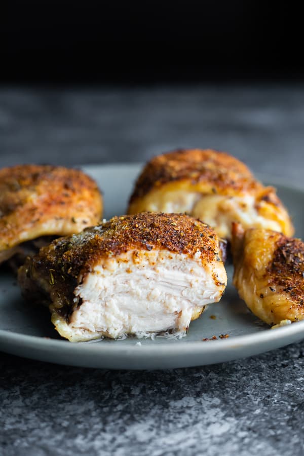 crispy baked chicken thigh cut in half on a gray plate