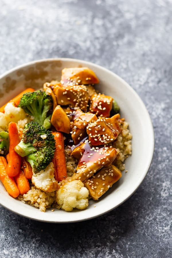 white bowl with roast veggies and chunks of chicken over quinoa