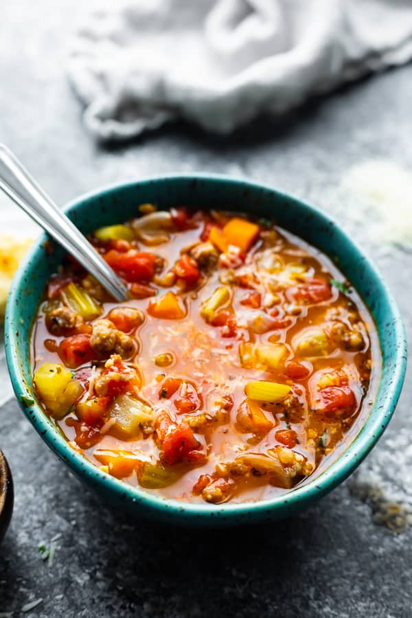 italian sausage soup in blue bowl with spoon