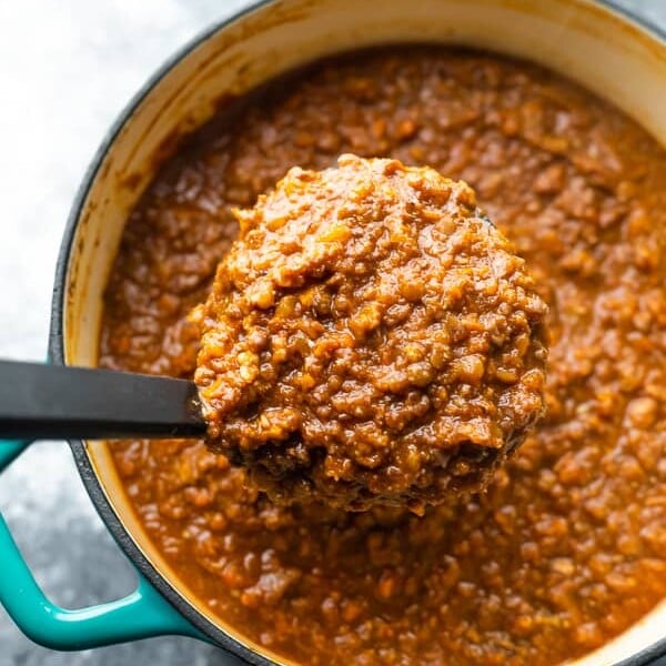 overhead shot of vegan bolognese in large le creuset pot with ladle