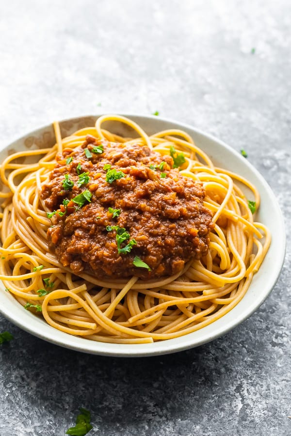 vegan bolognese sauce on spaghetti, in white bowl