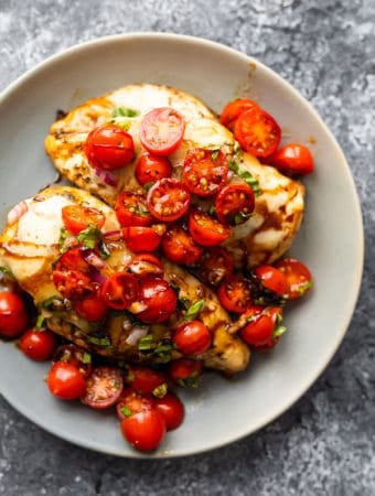 overhead shot of baked bruschetta chicken with cherry tomatoes on gray plate