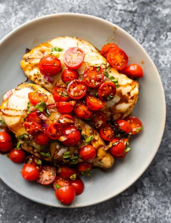 overhead shot of baked bruschetta chicken with cherry tomatoes on gray plate