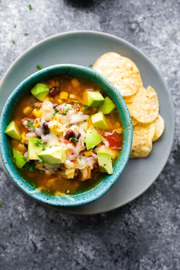 overhead view of the slow cooker taco soup recipe in bowl with avocado and tortilla chips