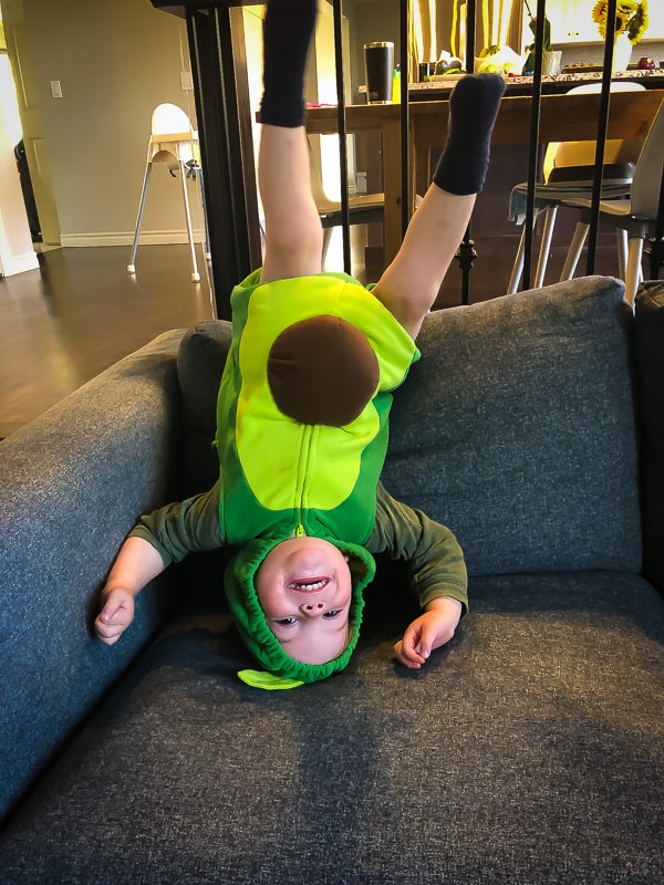 picture of a little boy in an avocado outfit upside down on the couch