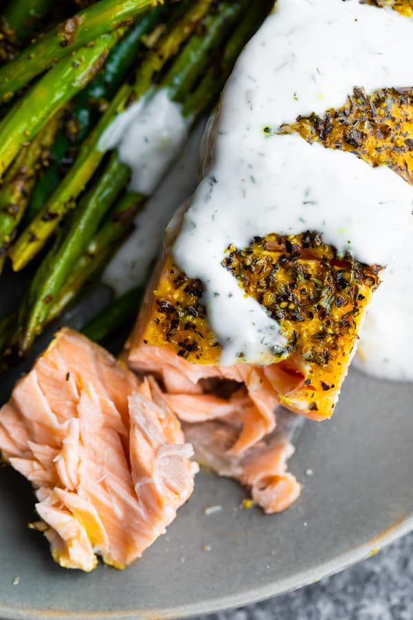 close up overhead shot of lemon pepper salmon drizzled with yogurt sauce