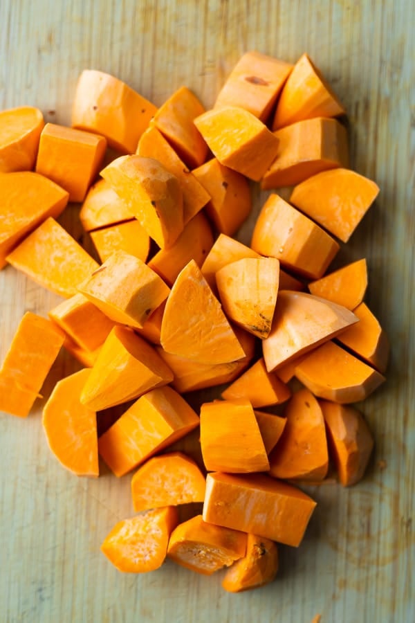 peeled sweet potatoes chopped into large 2 inch cubes on wooden cutting board from above