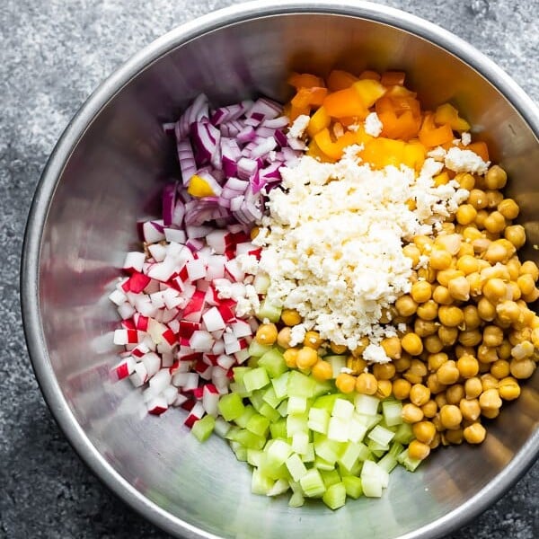 overhead shot of ingredients for chopped chickpea salad in large metal bowls