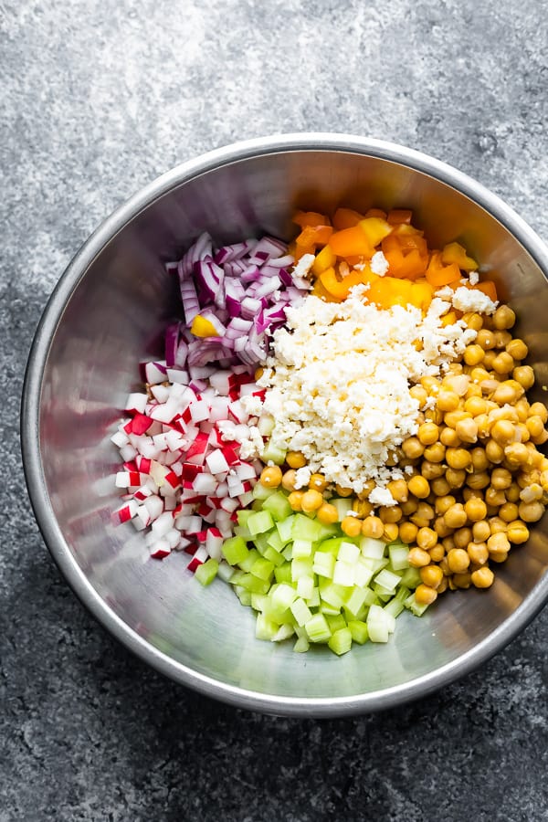 overhead shot of ingredients for chopped chickpea salad in large metal bowls