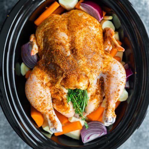 overhead shot of a whole chicken and veggies in a crockpot