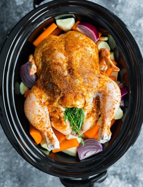 overhead shot of a whole chicken and veggies in a crockpot