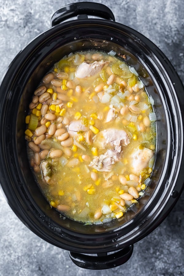 overhead view of ingredients for white bean chicken chili crockpot in slow cooker after cooking